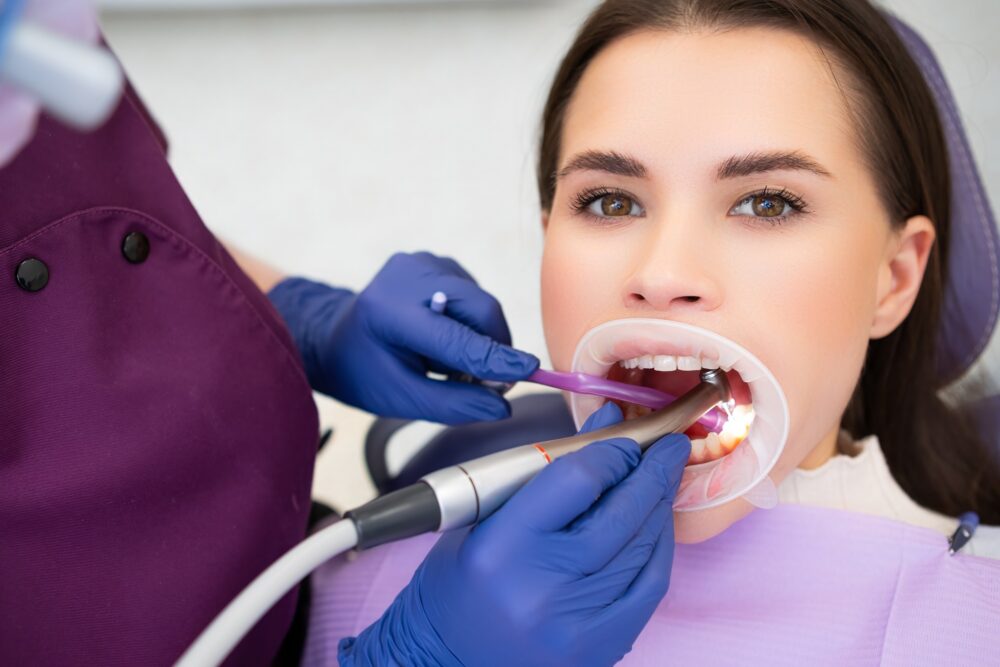 Dental hygienist performing a professional teeth cleaning on a patient in McKinney, TX